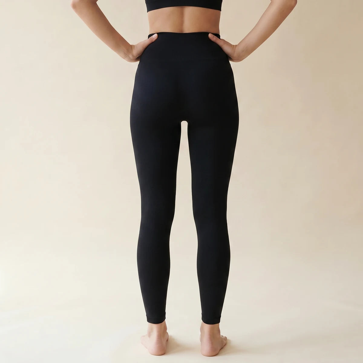 Legging amincissant noir Elya vue de dos, mains sur les hanches — galbe et maintien, taille haute seamless