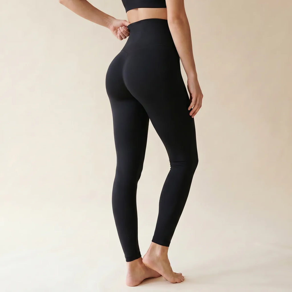 Legging taille haute gainant noir Elya vue de dos trois-quarts — ceinture sous la poitrine et fessier galbé
